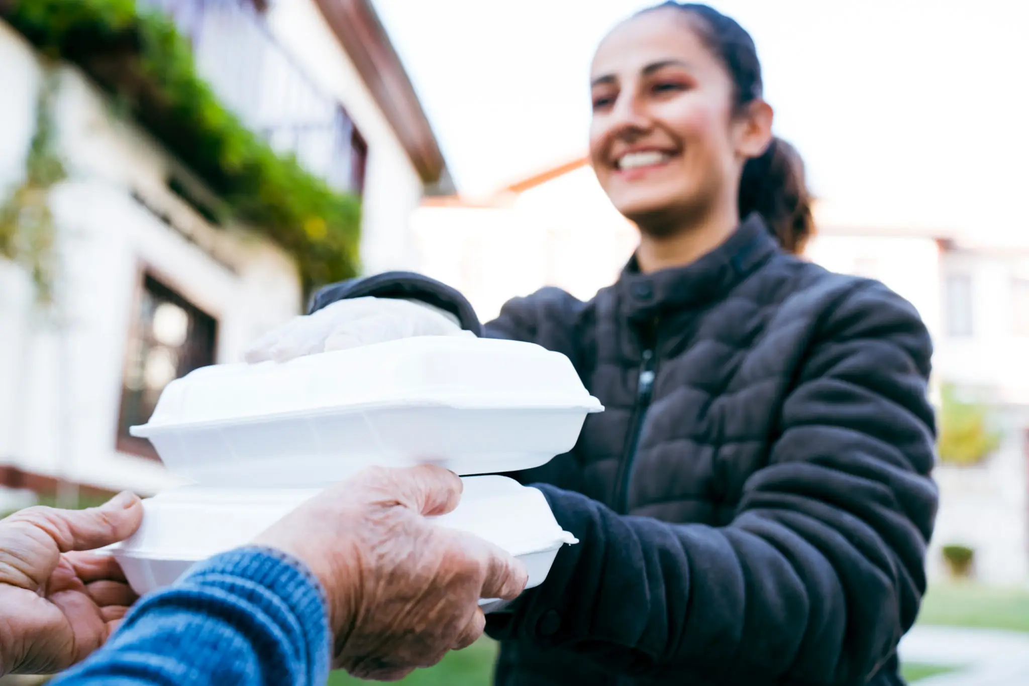 Volunteer Delivering Food To Elderly People During Lockdown. Close up of old woman receiving take away food delivery
